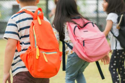 three-pupils-of-primary-school-go-hand-in-hand-boy-and-girl-with-school-bags-behind-the-back-beginning-of-school-lessons-warm-day-of-fall-back-to-school-little-first-graders