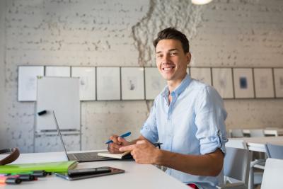 happy-remote-worker-young-handsome-man-thinking-writing-notes-in-notebook