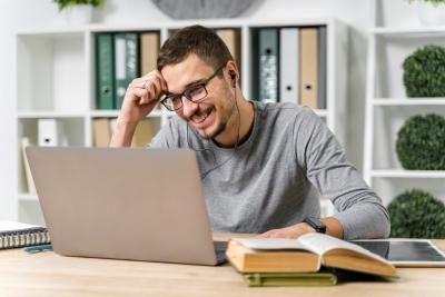medium-shot-smiley-guy-studying-with-his-laptop
